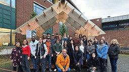 Timber Tectonics proposed shelter for Tualatin. Shows students smiling with city officials in front of the proposed structure. 