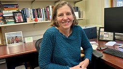 Diana Mason is shown in her office sitting and smiling to the camera. 