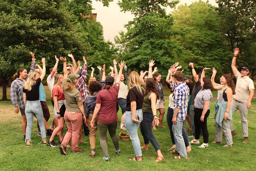 Photo of 2021's RARE service cohort. A large group of people raising their hands in a circle. 