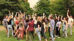 Photo of 2021's RARE service cohort. A large group of people raising their hands in a circle. 
