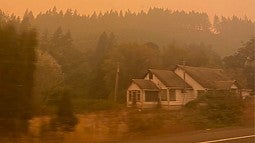 Smokey landscape in Oregon hills with a house in foreground