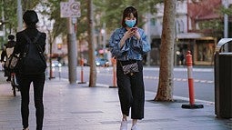 woman wearing mask walking down city street