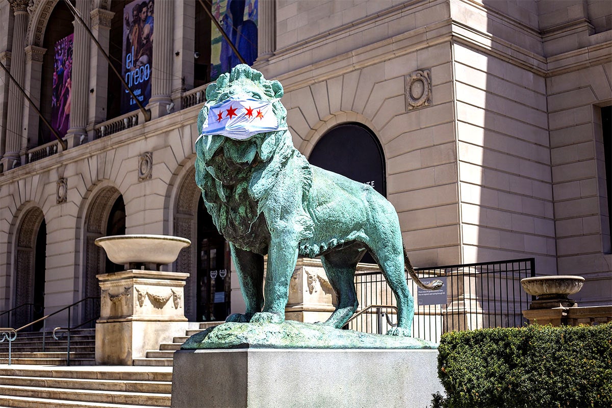 Photo of the exterior of a Chicago museum and lion statue with a mask